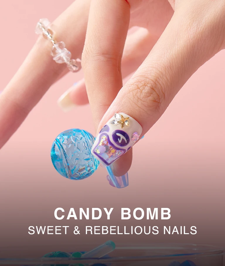 Close-up of a purple candy-themed press-on nail with heart-shaped embellishments and glossy top coat, worn on a hand holding a blue textured ball.