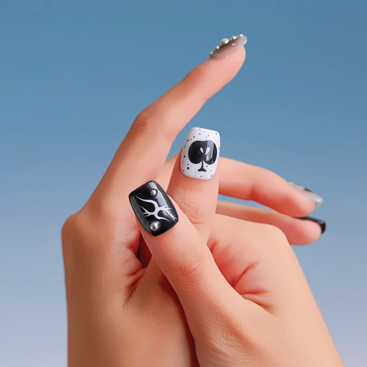 Close-up of Astro Courier press-on nails showing black flame artwork and black spade graphic on short square nails.