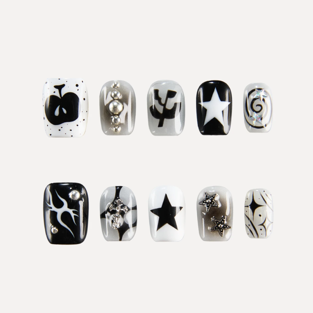 Flat lay of LOST in PARK Astro Courier short square press-on nails in black, white, and silver with star motifs, flames, graphic symbols, and 3D metallic studs.
