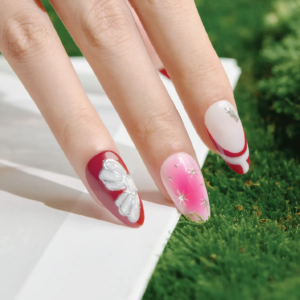 Close-up of Cherry Stardust medium almond press-on nails featuring pink gradient stars and red silver flower accents.”