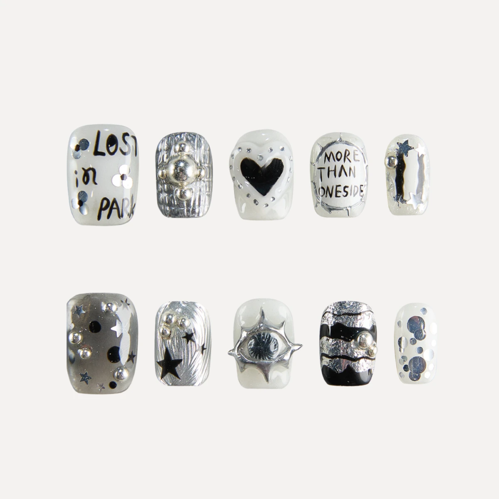Flat lay of 10 Chrome Vision short square press-on nails featuring silver chrome textures, handwritten text graphics, heart motif, star accents, and 3D metallic studs.
