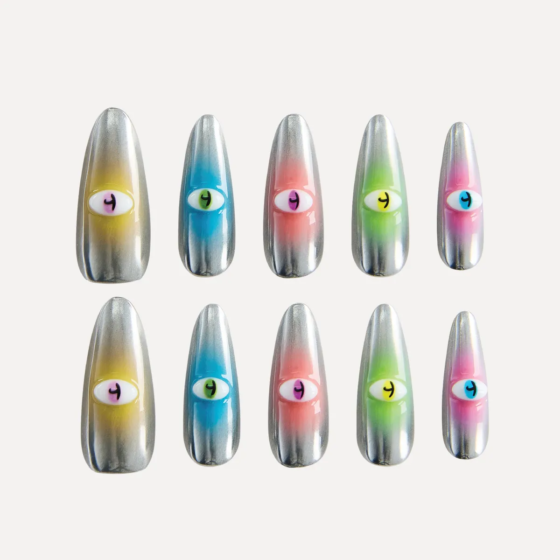 Flat-lay display of the “Cosmic Vigil” long almond press-on nail set with silver chrome gradients and colorful raised eye decorations in multiple hues.