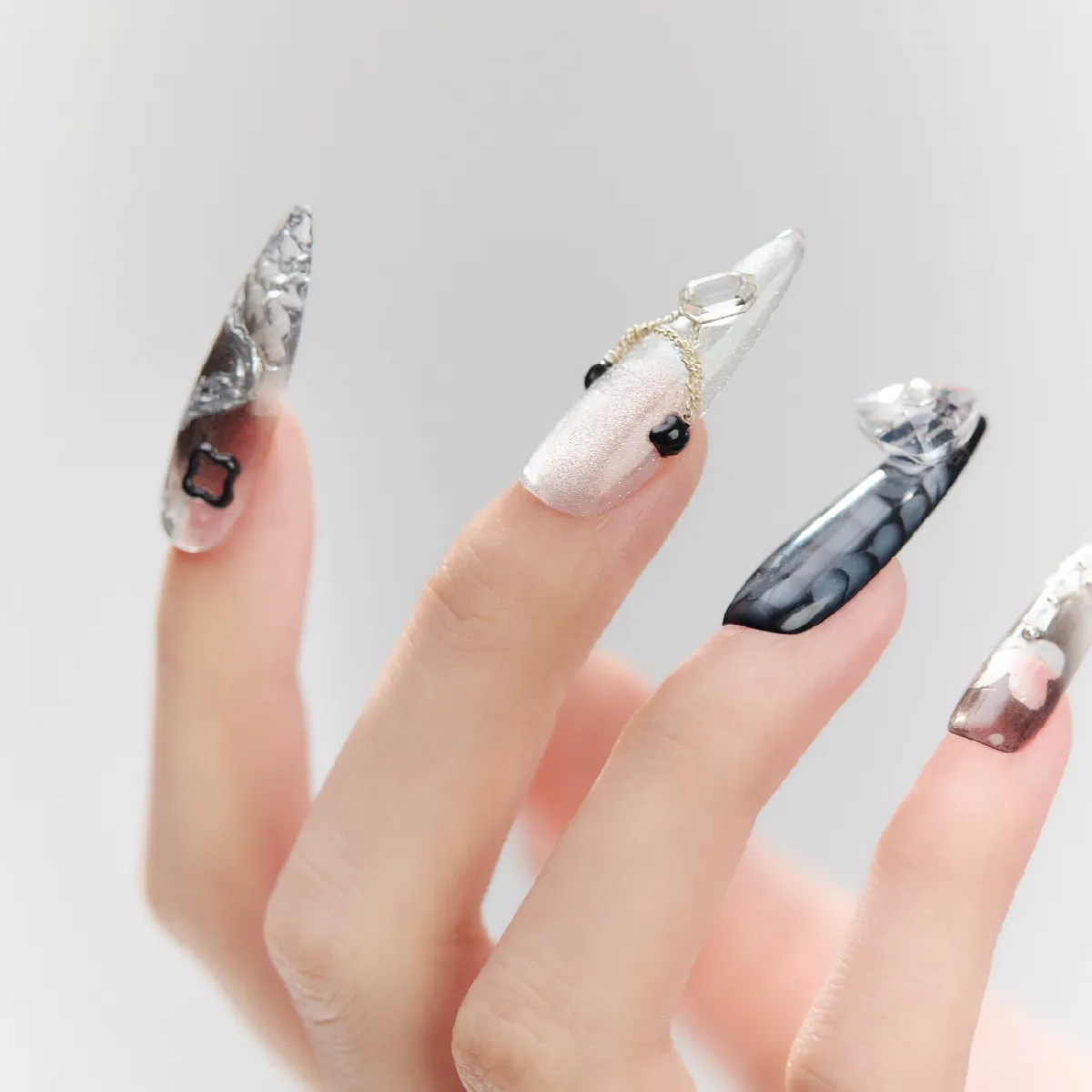 Detailed view of Cyber Pulse stiletto nails with gradient metallic finishes, 3D chain decorations, and bold chrome elements