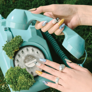 Deconstruct Vision press-on nails styled with a retro turquoise rotary phone, highlighting mixed abstract patterns and bold color blocking