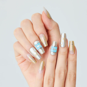 Hand wearing silver and gold press-on nails with blue 3D digital panel accents