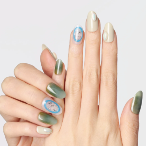Hand wearing green gradient and nude press-on nails with blue oval jelly accent design