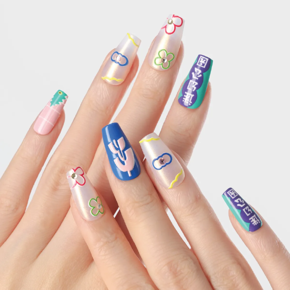 Hand showing pastel pearl nails with bright floral outlines and bold graphic accent nails