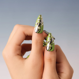 Close-up of thumb and index finger featuring green and silver lightning bolt press-on nails