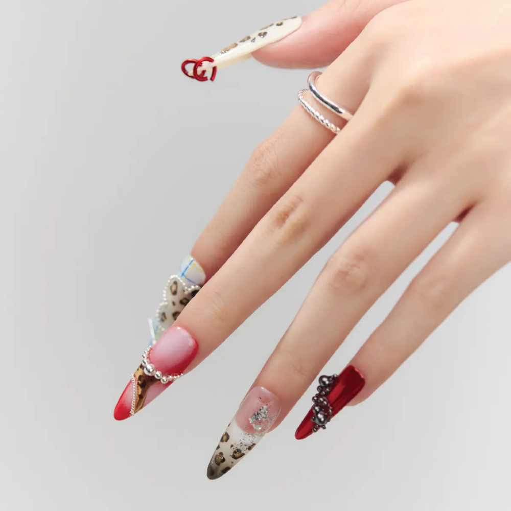 Close-up of Rouge Leopard press-on nails featuring 3D hearts, plaid patterns, and glitter details