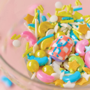 One press-on nail from LOST in PARK Starlight Bubble nestled in colorful candy-shaped decorations.