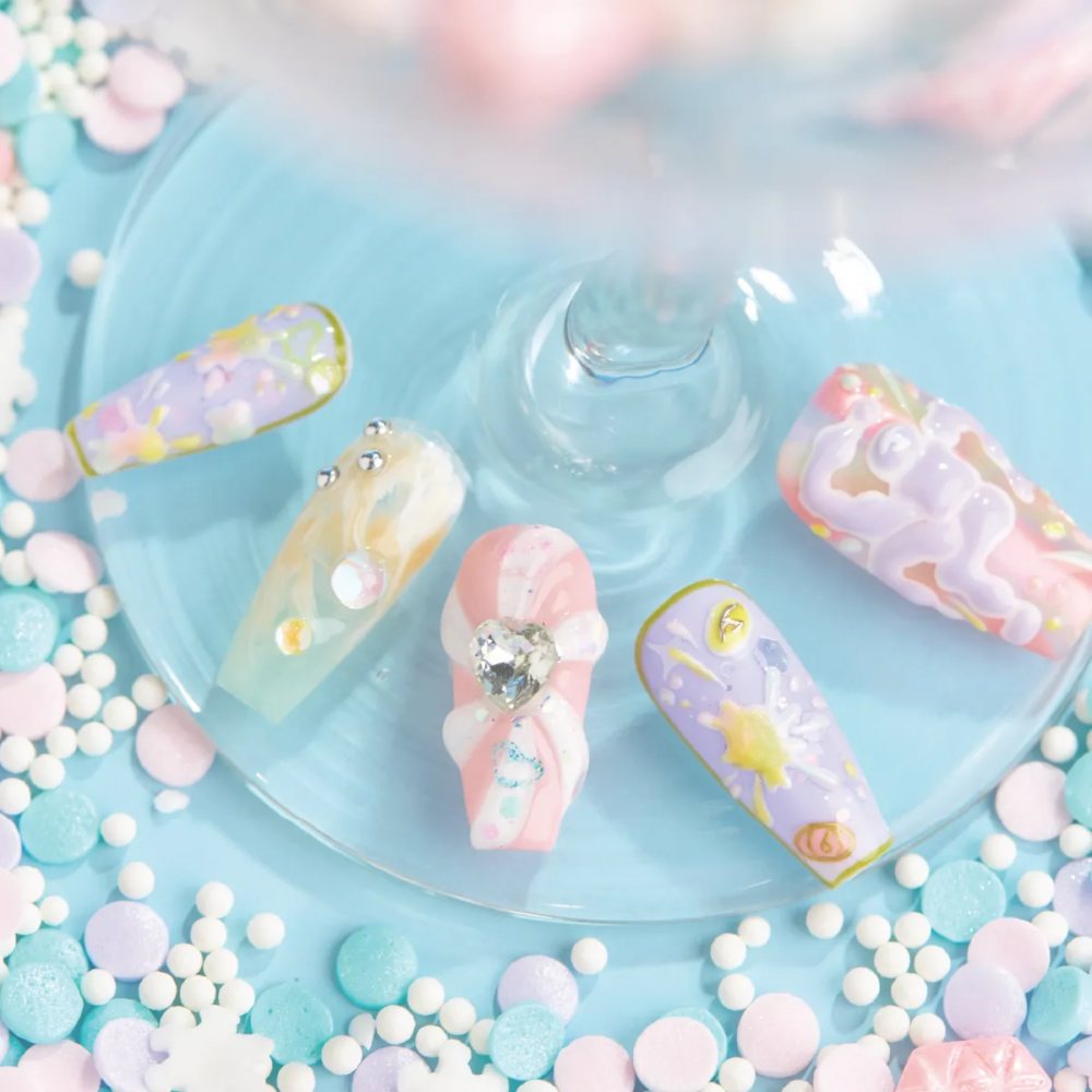 Set of 5 artisan press-on nails displayed on blue plate with pastel candy sprinkles.