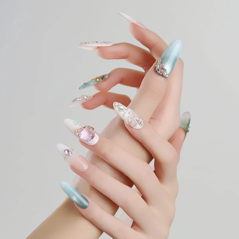 Mint green long oval press on nails worn on hands with crystal embellishments