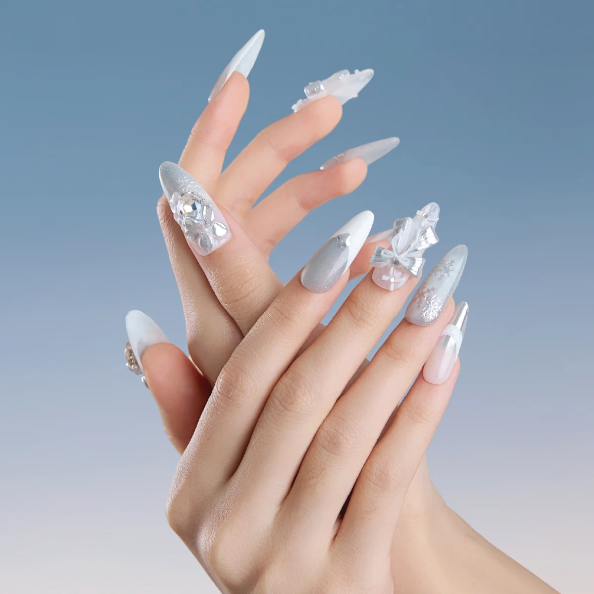 Long almond press on nails on hands with silver bow snowflake and frosted white details